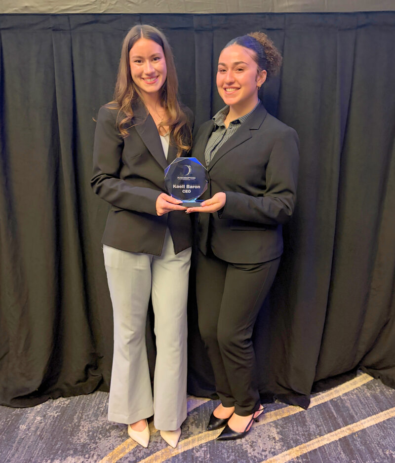 Two Raedemption Marketing team members holding a company award
